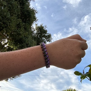May include: A purple and silver beaded bracelet with a wire wrap design.