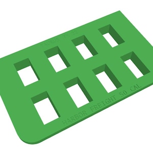 Puede incluir: Un objeto rectangular verde brillante con ocho recortes rectangulares. El texto "TAURUS TX 22" y "HARBOR FREIGHT 50 CAL" están impresos en la superficie. El objeto tiene esquinas redondeadas.