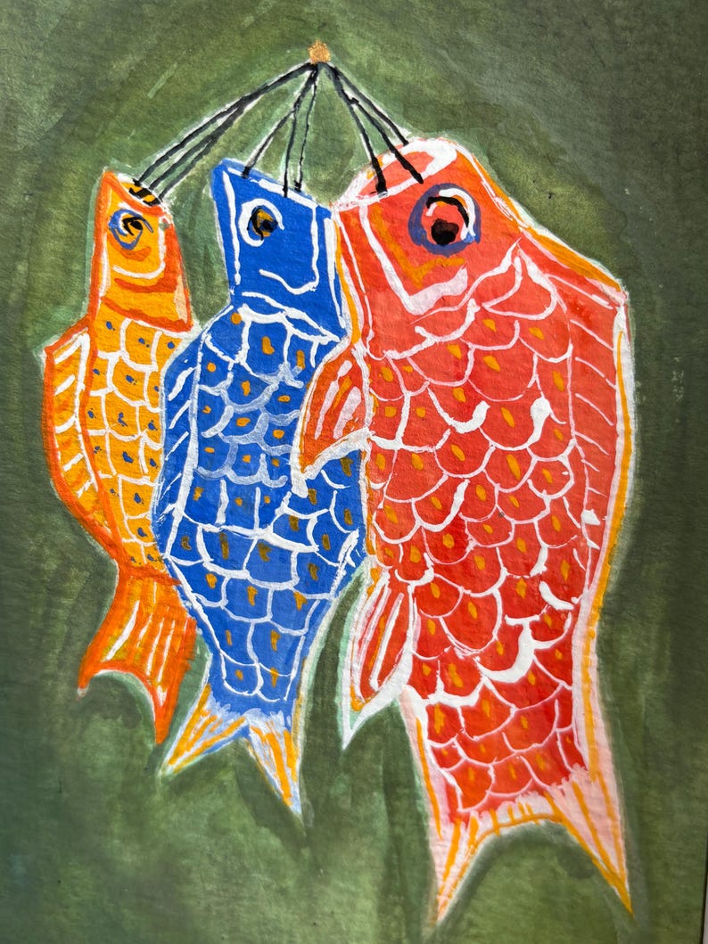 May include: Watercolor painting of three stylized fish in orange, blue, and red, suspended from black strings against a green background. The fish have detailed scales and are painted in a folk art style.