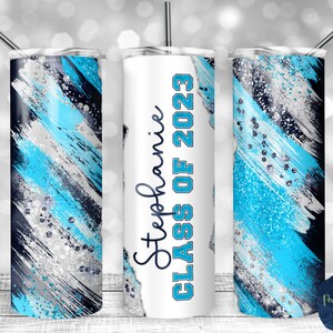 May include: A set of three stainless steel tumblers with a blue, silver, and black abstract design. The middle tumbler has the text "Stephanie Class of 2023" printed on it.