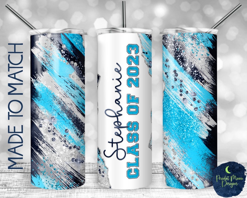 May include: A set of three stainless steel tumblers with a blue, silver, and black abstract design. The middle tumbler has the text "Stephanie Class of 2023" printed on it.