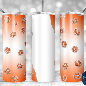 Op de afbeelding: Drie 20 ounce roestvrijstalen tumblers met een wit en oranje ombre-ontwerp. De tumblers zijn versierd met een patroon van oranje glitter-pootafdrukken.