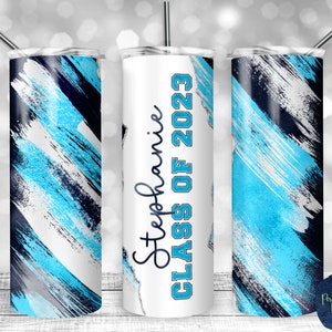 May include: A white tumbler with a blue and black abstract paint design. The tumbler has the text "Stephanie Class of 2023" on it.