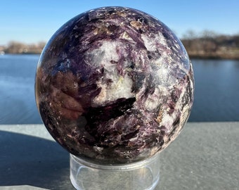 May include: A purple and white crystal sphere on a clear stand. The sphere has a swirling, layered pattern.