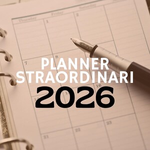Op de afbeelding: Een close-up van een open planner met de tekst "PLANNER STRAORDINARI 2026" in wit en zwart. Een zilveren en bruine pen ligt op de kalenderpagina's. De planner is opengeklapt op een maandoverzicht.