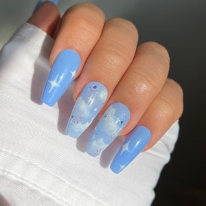 Könnte beinhalten: Lange, blaue und weiße Press-on-Nägel mit einem Wolken- und Sternendesign.