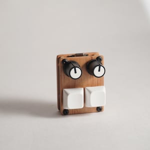 May include: A rectangular wooden controller featuring two black rotary knobs with white indicators on the top half and two large white square mechanical key switches on the bottom half, all secured with four black screws on the front panel.