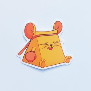 May include: A die-cut sticker featuring a cartoon character shaped like a yellow triangular wedge of cheese with mouse ears, a red headband, and red boxing gloves. The character has a smiling face with whiskers and is sitting in a forward-facing pose.