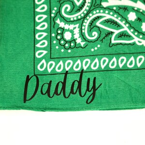 May include: Green bandana with a white paisley pattern and the word "Daddy" written in black cursive.
