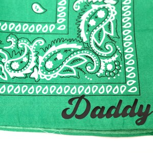 May include: Green bandana with a white paisley pattern and the word "Daddy" printed in black.