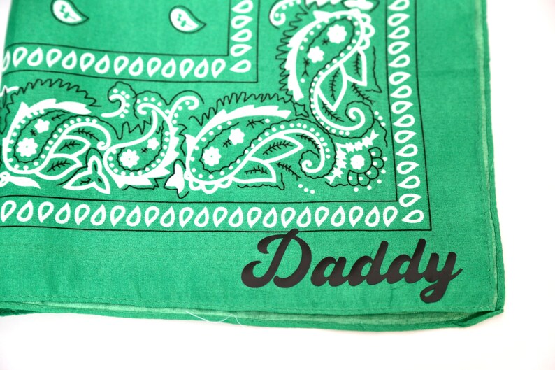 May include: Green bandana with a white paisley pattern and the word "Daddy" printed in black.