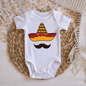 May include: White baby onesie with a yellow, red, and green sombrero and a black mustache printed on the front.
