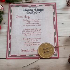 May include: A festive letter from Santa Claus, featuring a gold button. The letter has a red and green border and text. The button is inscribed with "Father Christmas". Christmas decorations, including baubles and pine cones, are nearby.