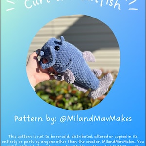 May include: A crocheted blue catfish plush toy with a black eye and a purple tail fin. The toy is being held by a hand. The text "Curt the Catfish!" is at the top of the image. The text "Pattern by: @MilandMavMakes" is at the bottom of the image. The text "This pattern is not to be re-sold, distributed, altered or copied in its entirety or parts by anyone other than the creator, MilandMavMakes. You MAY sell finished products made with this pattern, but PLEASE credit MilandMavMakes as the creator of the pattern!" is below the pattern by text.