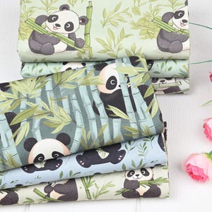 May include: Several folded fabrics with panda bear patterns. The designs feature pandas amongst bamboo on light green, blue, and white backgrounds. The pandas are depicted in black and white with a friendly expression.