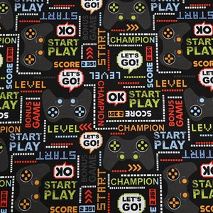 May include: Black fabric with a repeating pattern of video game controllers, pixelated text, and colourful graphics. The text includes "Start Play", "Level", "Bonus Game", "Champion", "Let's Go!" and "Score 2 351".
