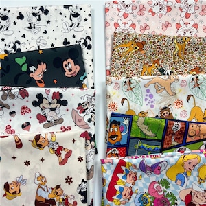 Puede incluir: Una colección de paneles de tela con temática de Disney que presentan varios personajes como Mickey Mouse, Bambi y Alicia en el país de las maravillas. Las telas muestran una variedad de patrones y colores, incluyendo negro, blanco, rosa y azul. Ideal para manualidades y costura.