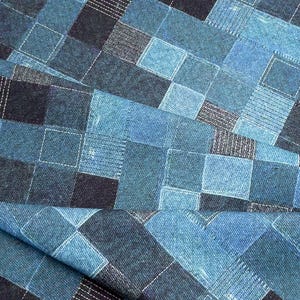May include: A fabric featuring a patchwork design of various blue denim squares. The pattern consists of alternating shades of light, medium, and dark blue, with visible white stitching outlining each individual square across the textile surface.