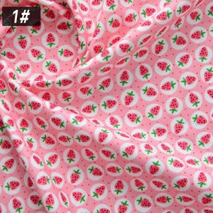 Puede incluir: Tela rosa con un patr&oacute;n repetido de fresas rojas con tallos verdes, dentro de c&iacute;rculos blancos y peque&ntilde;os puntos rojos. El n&uacute;mero "1#" est&aacute; en un cuadro negro en la esquina superior izquierda.