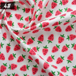 Puede incluir: Tela blanca con un patr&oacute;n repetido de fresas rojas y hojas verdes. Las fresas tienen semillas negras y est&aacute;n dispersas por la tela. El n&uacute;mero "4#" est&aacute; en la esquina superior izquierda.