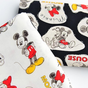 Peut inclure: Deux morceaux de tissu avec des personnages Disney. L'un est blanc avec Mickey Mouse en short rouge et chaussures jaunes. L'autre est noir avec Minnie Mouse et Pluto en contours blancs. Le texte "Minnie" et "Mouse" apparaît en jaune et rouge.
