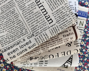 May include: A stack of fabric scraps with newspaper print designs. The top scrap features the text "salesman's even loved at he cons suc" and the bottom scrap features the text "Daddy bear" and "Mummy Daddy bear".