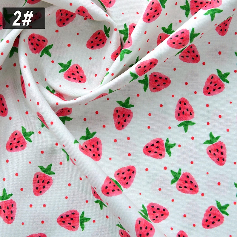 Puede incluir: Tela blanca con un patr&oacute;n repetido de fresas rojas y peque&ntilde;os puntos rojos. Las fresas tienen tallos verdes y semillas negras. El n&uacute;mero "2#" est&aacute; en un cuadro negro en la esquina superior izquierda.