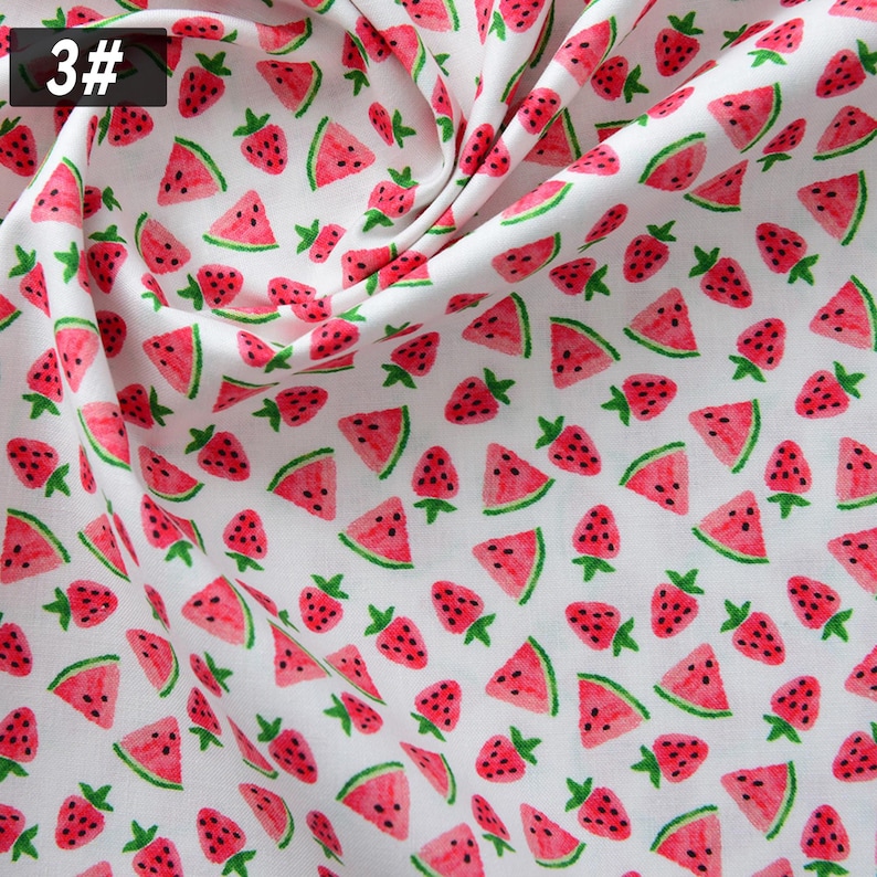 Puede incluir: Tela blanca con un patr&oacute;n repetido de rodajas de sand&iacute;a rojas y fresas con tallos verdes. La tela tiene un aspecto suave y fluido. El n&uacute;mero "3#" est&aacute; en la esquina superior izquierda.