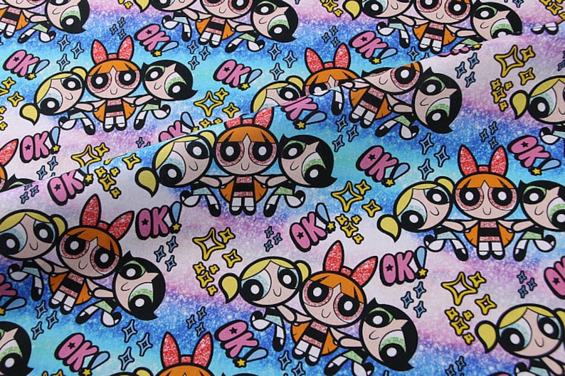 Puede incluir: Una tela colorida con un patr&oacute;n repetitivo de tres chicas de dibujos animados con coletas y la palabra "OK!" en un fondo degradado rosa, azul y morado. Las chicas llevan vestidos negros con detalles blancos y tienen ojos grandes y sonrisas.