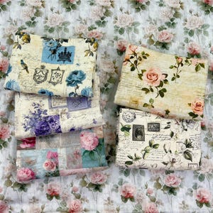 May include: Four folded pieces of fabric featuring vintage-style floral patterns, script handwriting, and postage stamp motifs. The designs include blue, purple, pink, and peach roses, along with decorative frames and bird illustrations on cream backgrounds.