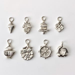 Peut inclure: Huit breloques en argent avec différents motifs, dont un coquillage, une fleur, une roue, un poisson, un stupa, un nœud, un vase et une fleur de lotus.