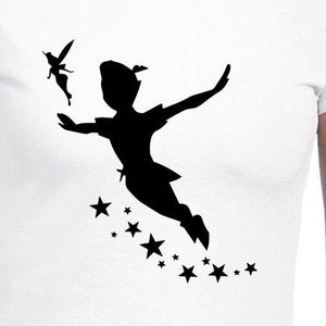 May include: A white t-shirt with a black silhouette of Peter Pan flying with Tinkerbell and stars.