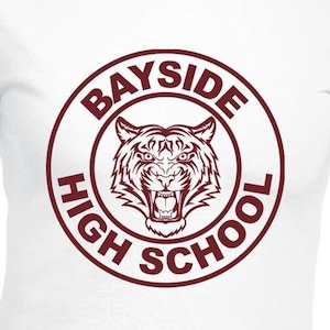 Puede incluir: Camiseta blanca con un gráfico circular marrón que presenta una cabeza de tigre y el texto "Bayside High School".