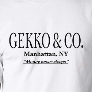 May include: White t-shirt with black text that reads "GEKKO & CO. Manhattan, NY "Money never sleeps""