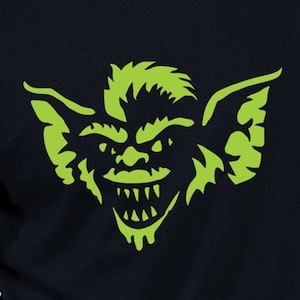 May include: A black t-shirt with a green graphic of a creature with large ears and a toothy grin.