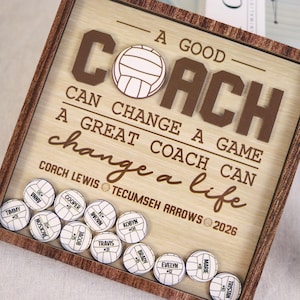 May include: Wooden framed sign with the words "A Good Coach Can Change A Game, A Great Coach Can Change A Life." Includes volleyball-shaped magnets with player names and numbers. The sign is light brown with dark brown lettering.