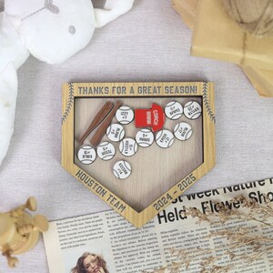 K&ouml;nnte beinhalten: Ein Baseball-Display aus Holz mit dem Text "THANKS FOR A GREAT SEASON!" und "HOUSTON TEAM 2024-2025." Es zeigt Baseb&auml;lle mit Spielernamen und -nummern, zwei Holzschl&auml;ger und ein rotes "COACH"-Schild.
