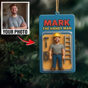 May include: A personalized Christmas ornament featuring a handyman figure in a blue package with the text "MARK THE HANDY MAN." The ornament includes a photo area labeled "YOUR PHOTO" and a miniature hammer, ladder, and other tools.