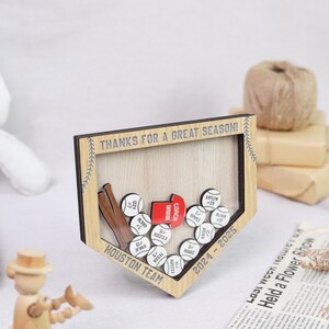 K&ouml;nnte beinhalten: Ein Baseball-Display aus Holz mit dem Text "THANKS FOR A GREAT SEASON!" und "HOUSTON TEAM". Es zeigt Baseb&auml;lle mit Namen und Nummern, zwei Schl&auml;ger und eine rote Trainerkarte. Der Rahmen ist hellbraun.