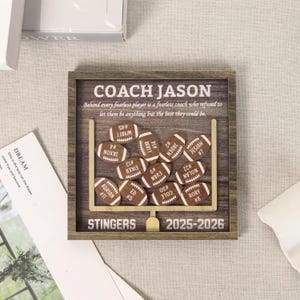 Może przedstawiać: Kwadratowa drewniana ramka typu shadow box z grafiką słupk&oacute;w bramki do futbolu amerykańskiego. Tekst głosi COACH JASON, Behind every fearless player is a fearless coach who refused to let them be anything but the best they could be, STINGERS, 2025-2026.