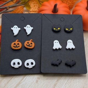 Peut inclure: Deux cartes de présentation noires avec six paires de boucles d'oreilles sur le thème d'Halloween. Les motifs incluent des fantômes blancs, des citrouilles orange, des crânes blancs, des chats noirs aux yeux jaunes et des chauves-souris.