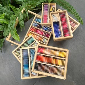 May include: Wooden storage boxes filled with colourful embroidery floss spools. The boxes are stacked on top of each other and are arranged in a rainbow pattern.