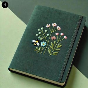 May include: A dark green journal with a floral embroidery design featuring a bee, flowers, and leaves. The journal has a sewn binding and a ribbon bookmark.