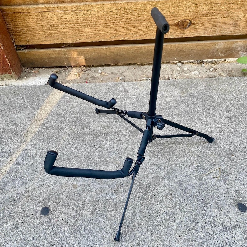 Puede incluir: Un soporte de guitarra de metal negro con una base de tr&iacute;pode de tres patas, un poste de soporte vertical con un apoyo superior y dos brazos inferiores. Todos los puntos de contacto est&aacute;n cubiertos con espuma negra para proteger el instrumento.