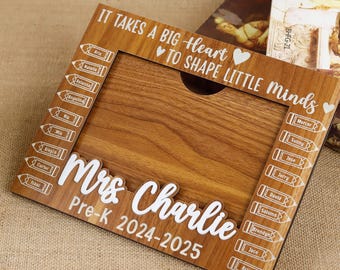 May include: Wooden picture frame with the text "IT TAKES A BIG HEART TO SHAPE LITTLE MINDS" and "Mrs Charlie Pre-K 2024-2025". The frame has a wood grain finish and includes pencil-shaped name tags.