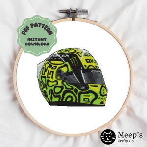May include: Cross-stitch design of a racing helmet in a wooden hoop. The helmet is yellow and black with a green swirl pattern. The text "PDF PATTERN INSTANT DOWNLOAD" is on a green circle.