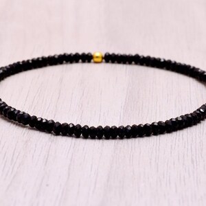 May include: A black beaded necklace with a gold clasp.