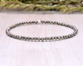 May include: A delicate bracelet made with small, faceted pyrite beads. The bracelet is silver in color and has a simple, minimalist design.