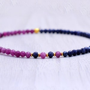 May include: A delicate bracelet made with small, faceted gemstone beads. The bracelet is half pink and half blue, with a gold accent in the center.