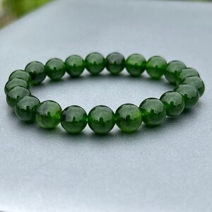 May include: A green gemstone bracelet with round beads. The bracelet is made of natural stones and is a beautiful accessory for any occasion.